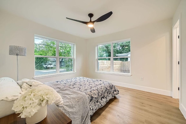bedroom featuring a ceiling fan, baseboards, and light wood finished floors