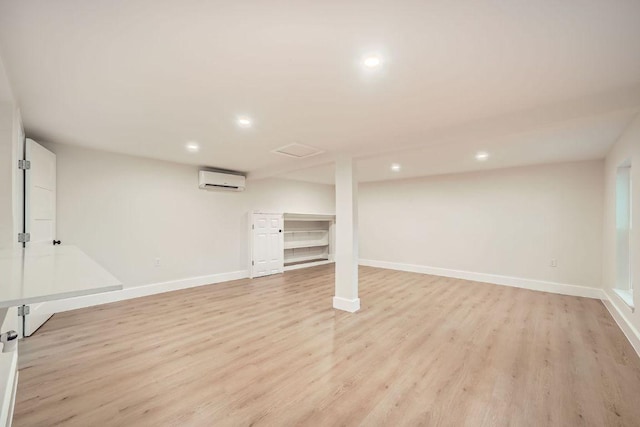 finished below grade area featuring recessed lighting, light wood-style floors, baseboards, and a wall mounted air conditioner