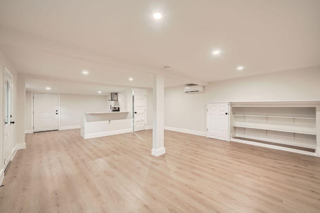 finished below grade area with an AC wall unit, recessed lighting, baseboards, and light wood-style floors