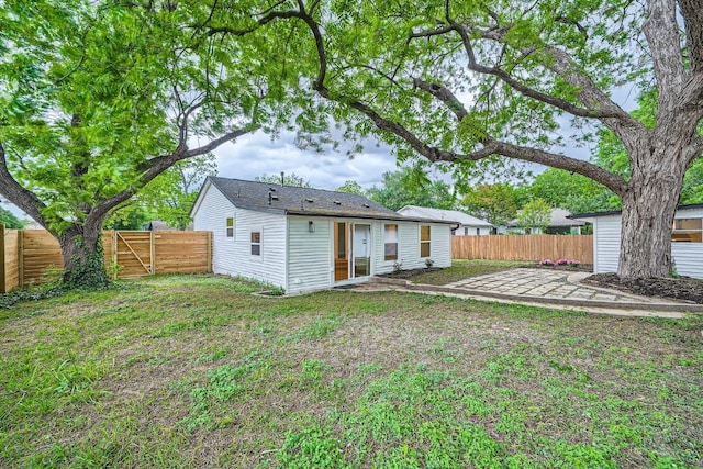 back of property with a patio, a fenced backyard, and a lawn
