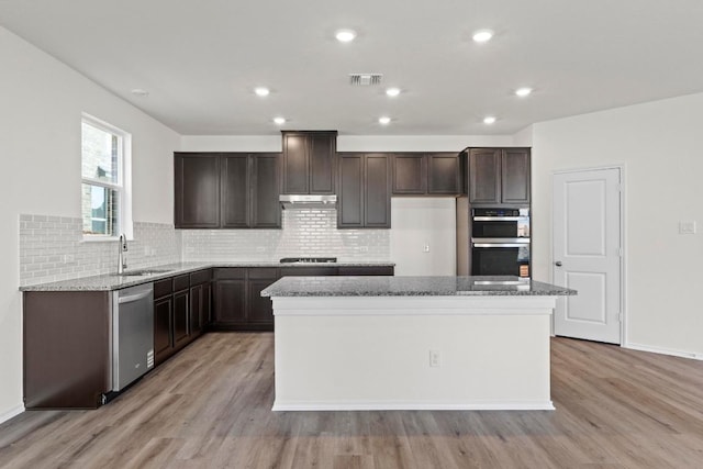 3756 Liberi Ln, Round Rock, TX 78665 - kitchen with appliances with stainless steel finishes, a sink, light wood-type flooring, a center island, and dark brown cabinetry