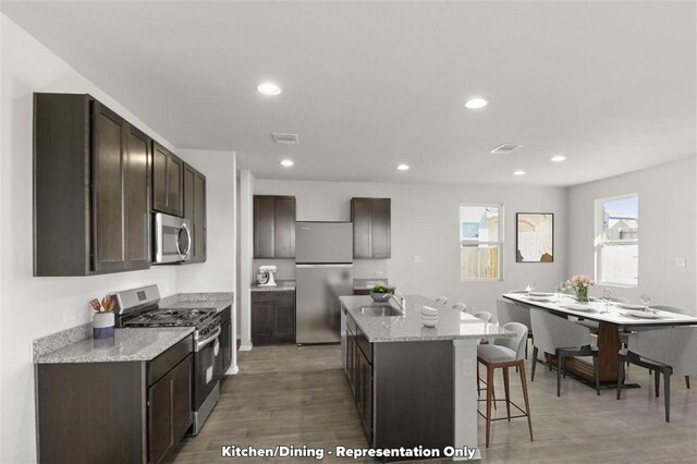 2605 Sam Bass Rd Unit 56, Round Rock, TX 78681 - kitchen with appliances with stainless steel finishes, dark brown cabinetry, an island with sink, light wood finished floors, and recessed lighting