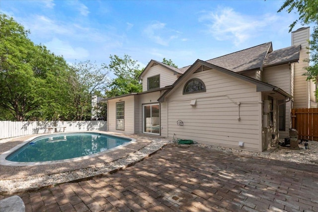 back of house with a chimney, a fenced backyard, a fenced in pool, and a patio area