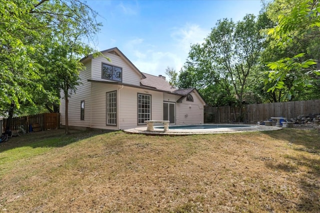 rear view of house featuring a chimney, a fenced in pool, a fenced backyard, and a yard
