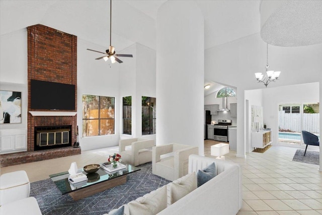 living area featuring tile patterned floors, high vaulted ceiling, ceiling fan with notable chandelier, and a brick fireplace