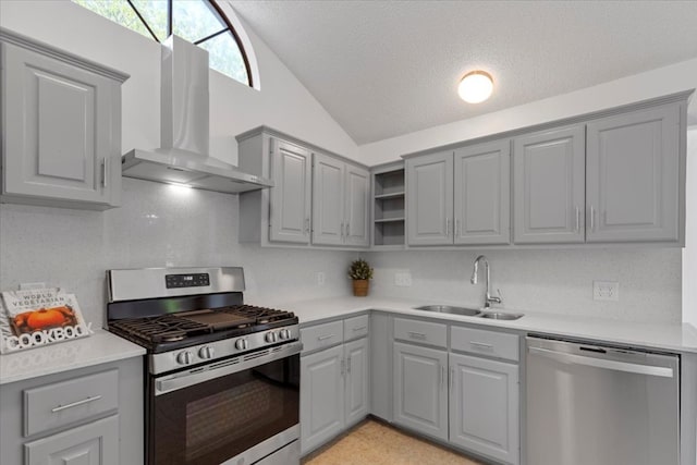 kitchen with wall chimney range hood, a sink, gray cabinets, and stainless steel appliances