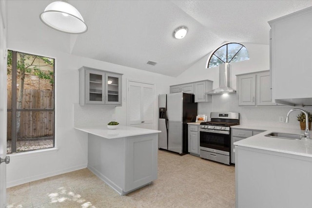 kitchen with stainless steel appliances, a wealth of natural light, a sink, gray cabinetry, and wall chimney exhaust hood