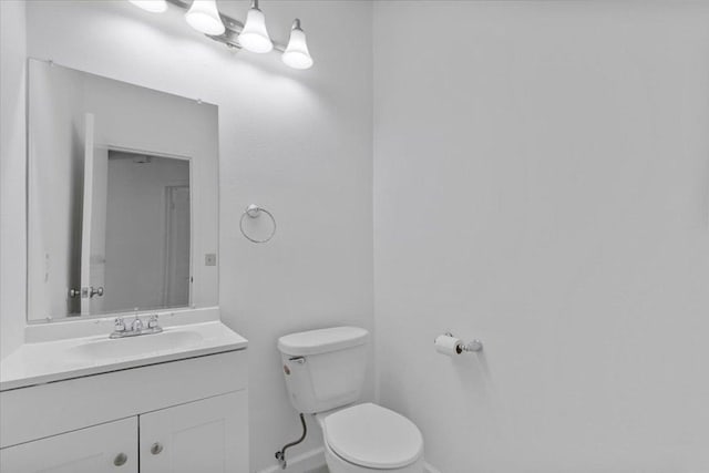 half bathroom with baseboards, toilet, and vanity