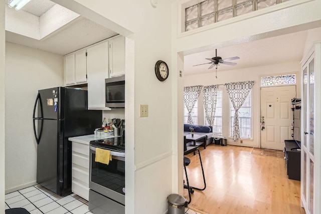 kitchen with light wood finished floors, a ceiling fan, white cabinetry, light countertops, and appliances with stainless steel finishes