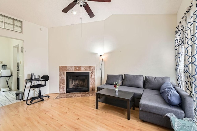 living room with ceiling fan, vaulted ceiling, wood finished floors, and a fireplace