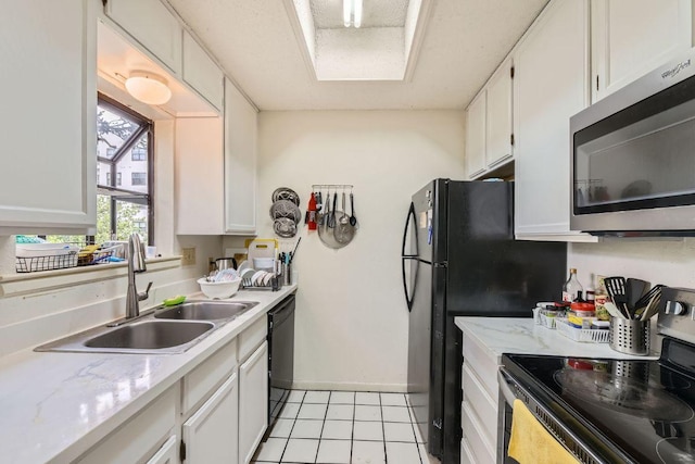 kitchen featuring baseboards, light tile patterned floors, appliances with stainless steel finishes, a sink, and white cabinetry