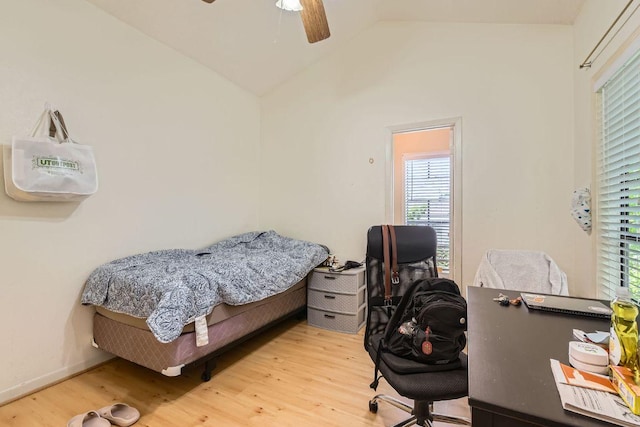 bedroom with wood finished floors, vaulted ceiling, and multiple windows