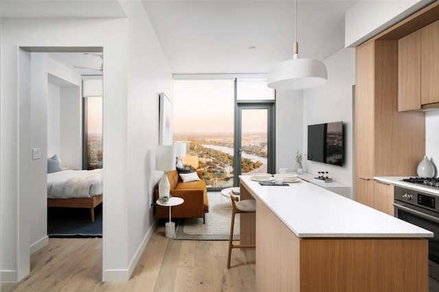 kitchen with light countertops, a kitchen island, appliances with stainless steel finishes, and light wood finished floors