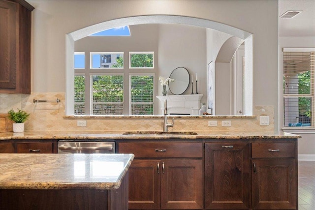 4211 Front Range Ln, Austin, TX 78732 - kitchen with light stone counters, stainless steel dishwasher, a sink, visible vents, and arched walkways