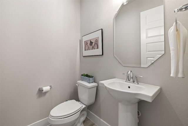 bathroom with baseboards, a sink, wood finished floors, and toilet