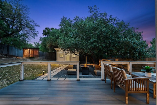 wooden deck featuring a storage shed, an outdoor living space with a fire pit, an outdoor structure, and a fenced backyard