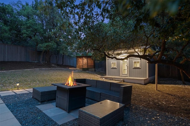 view of patio / terrace with an outbuilding, a fenced backyard, and an outdoor living space with a fire pit
