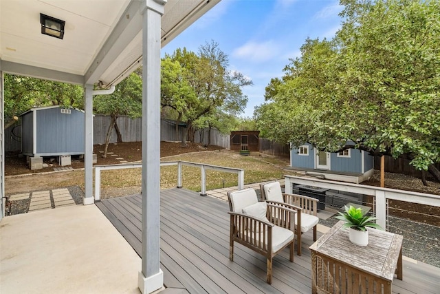 wooden terrace with a fenced backyard, a storage unit, an outdoor structure, and outdoor lounge area