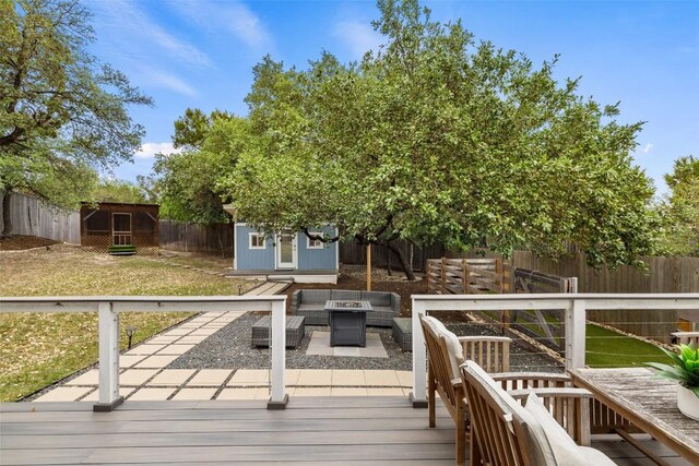 deck with an outbuilding, a fenced backyard, an outdoor living space with a fire pit, a yard, and a storage unit