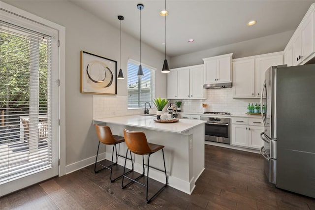 kitchen featuring appliances with stainless steel finishes, white cabinets, backsplash, and under cabinet range hood
