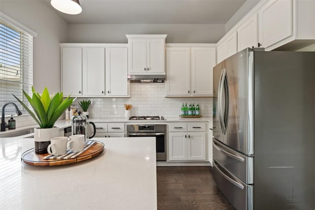 kitchen featuring dark wood-style floors, light countertops, under cabinet range hood, white cabinets, and appliances with stainless steel finishes