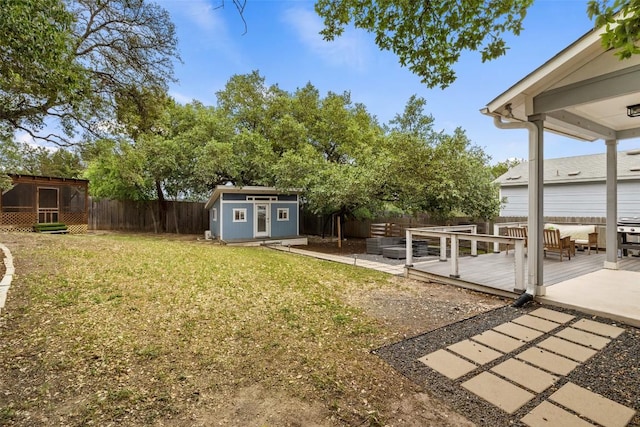 view of yard with an outdoor structure, a fenced backyard, a shed, and a deck