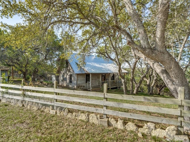 view of front facade with metal roof, a fenced front yard, covered porch, and log exterior