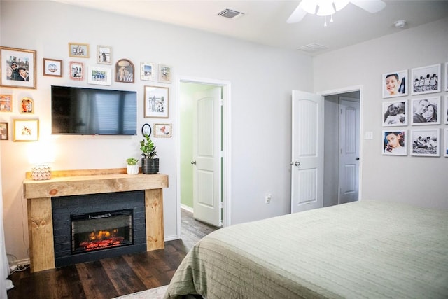 bedroom with a fireplace, visible vents, ceiling fan, and dark wood-type flooring