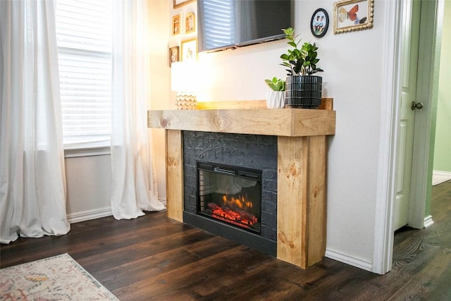 details with baseboards, wood finished floors, and a glass covered fireplace