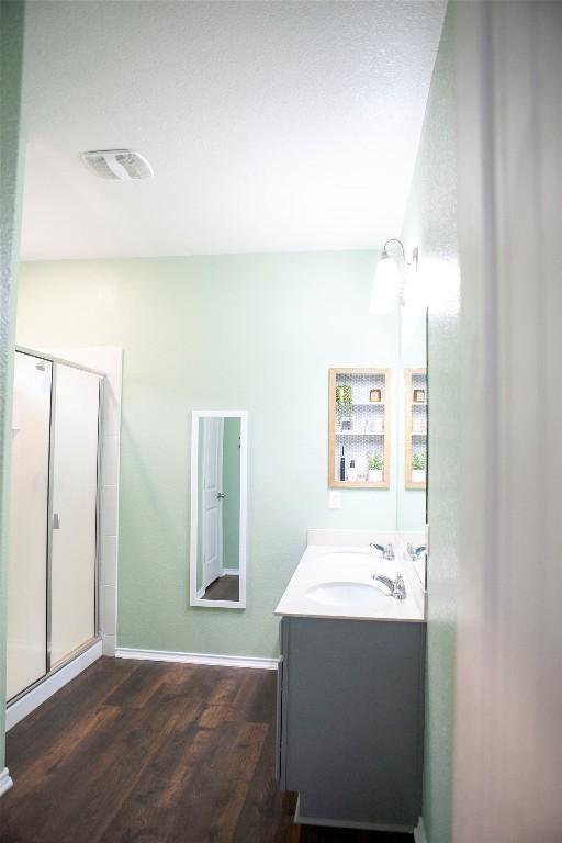 full bath with a shower stall, vanity, visible vents, baseboards, and wood finished floors