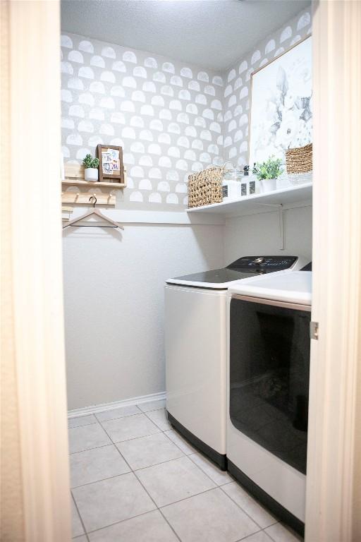 laundry room with light tile patterned floors, separate washer and dryer, laundry area, and baseboards