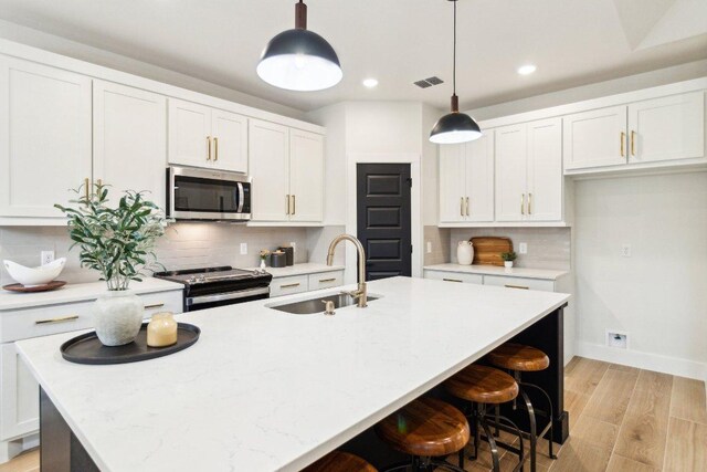 kitchen featuring recessed lighting, a sink, decorative backsplash, white cabinets, and appliances with stainless steel finishes