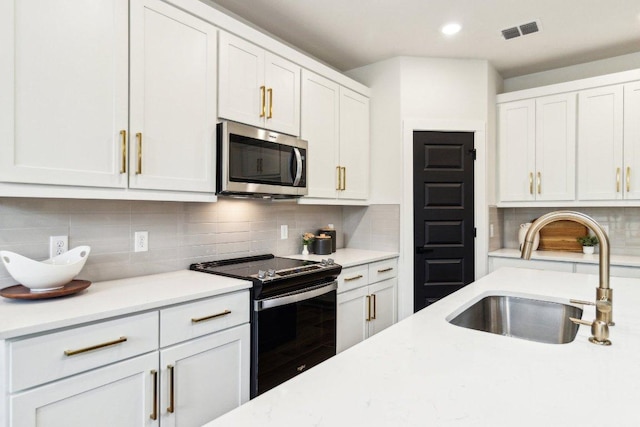 kitchen featuring electric range oven, a sink, backsplash, and stainless steel microwave