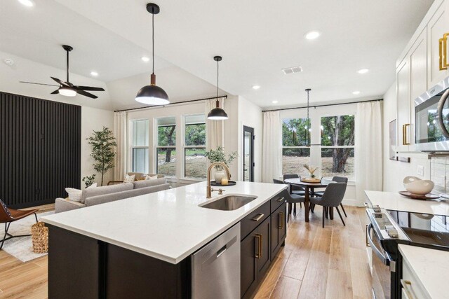 kitchen with light wood finished floors, recessed lighting, a sink, pendant lighting, and appliances with stainless steel finishes