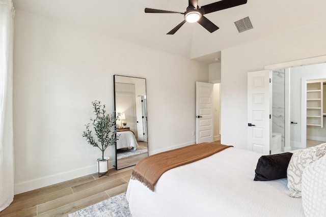 bedroom featuring light wood-type flooring, a walk in closet, baseboards, visible vents, and a ceiling fan