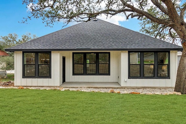 rear view of house with a shingled roof and a lawn