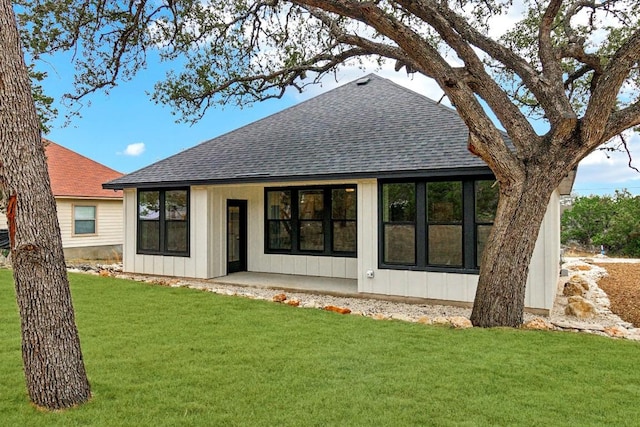 back of house featuring a yard, a shingled roof, and board and batten siding