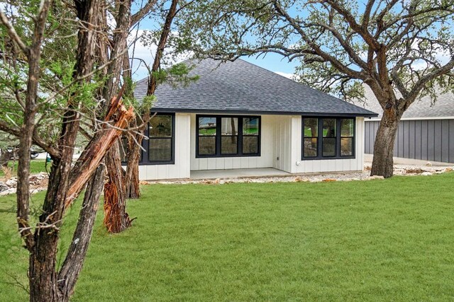 1313 Green Meadow Ln, Spring Branch, TX 78070 - back of property featuring a shingled roof, a lawn, a patio, and board and batten siding