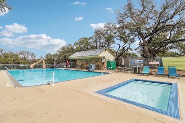 community pool featuring a patio area, a water slide, and fence