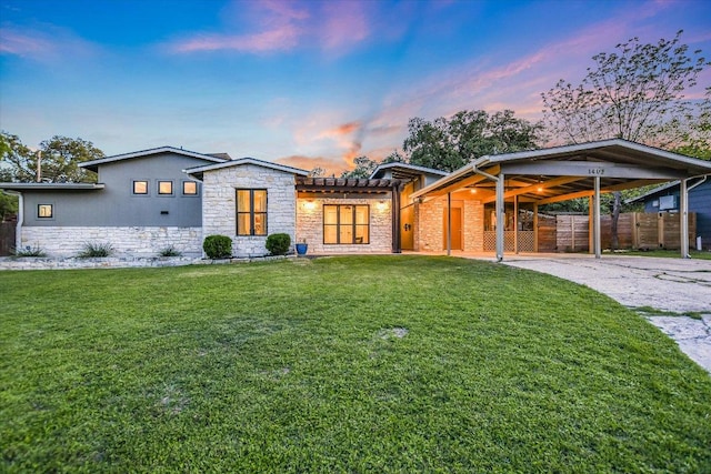 view of front of house featuring fence, an attached carport, a lawn, and stone siding