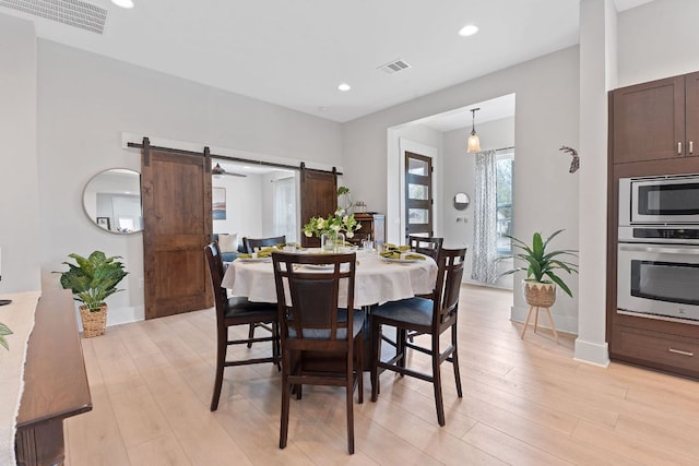 dining space with recessed lighting, visible vents, a barn door, and light wood-type flooring
