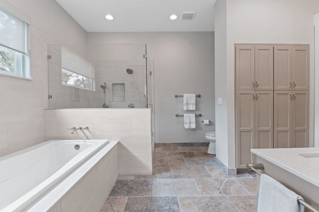 full bath featuring toilet, visible vents, tiled shower, a bath, and stone tile flooring