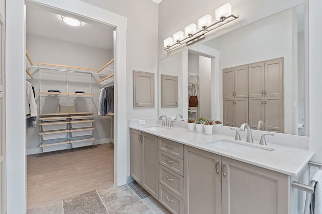 bathroom with a sink, baseboards, double vanity, and wood finished floors