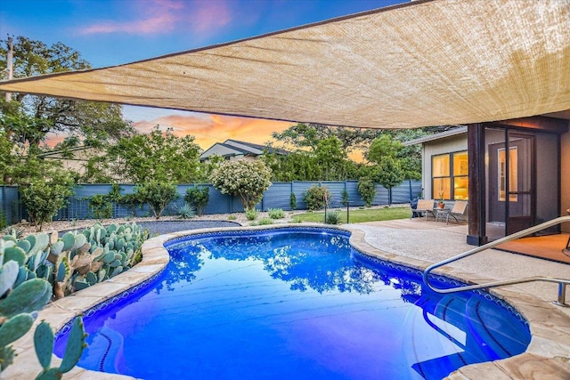 pool at dusk with a patio, a fenced in pool, and a fenced backyard