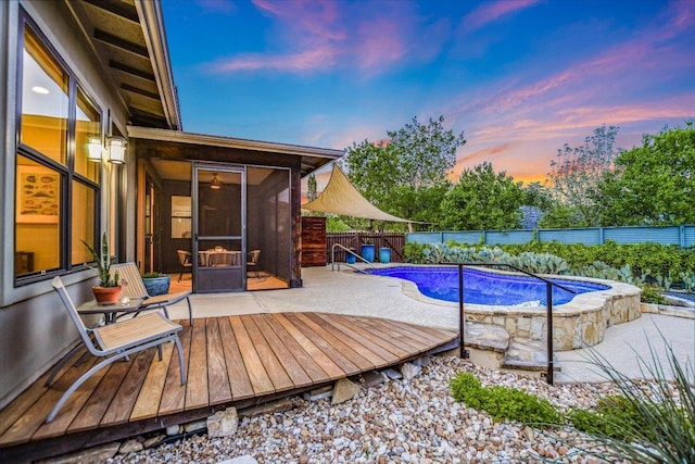 pool at dusk featuring a deck, a fenced in pool, a fenced backyard, and a sunroom