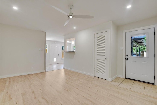 foyer featuring a ceiling fan, baseboards, and light wood finished floors