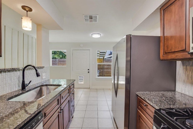 kitchen with backsplash, visible vents, a sink, dark stone countertops, and stainless steel appliances