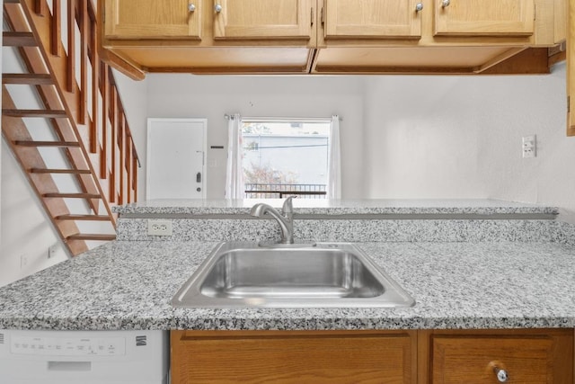 kitchen featuring light stone counters, dishwasher, and a sink