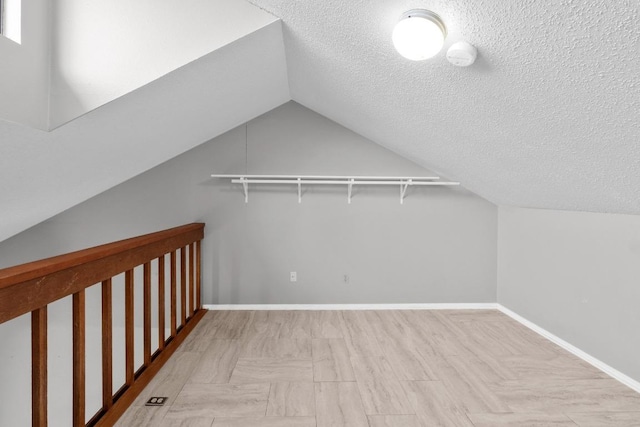 bonus room featuring a textured ceiling, lofted ceiling, and baseboards