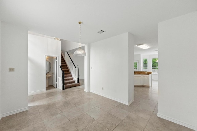 interior space with light tile patterned flooring, visible vents, stairway, and baseboards